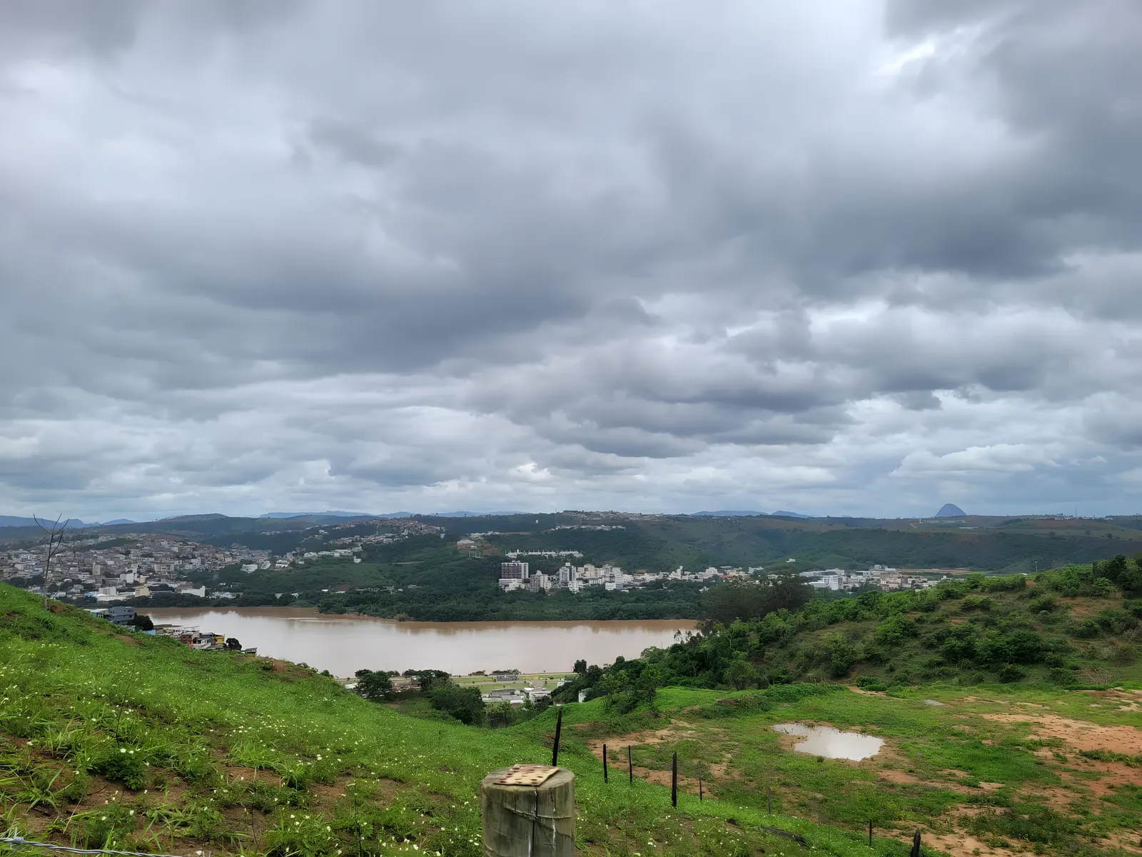 O Rio Doce visto do alto de um morro em Colatina, com a cidade ao fundo e o céu carregado